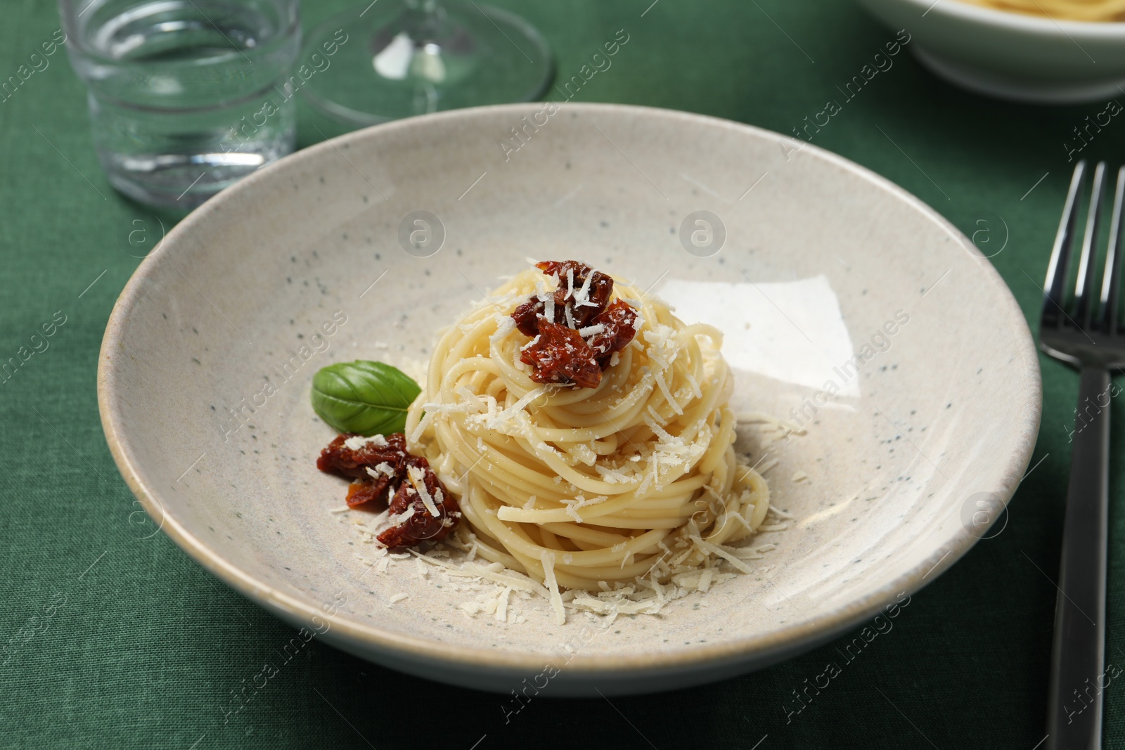 Photo of Tasty spaghetti with sun-dried tomatoes and parmesan cheese served on table, closeup. Exquisite presentation of pasta dish