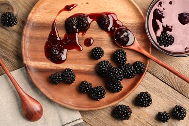 Photo of Tasty blackberry jam and fresh berries on wooden table, flat lay
