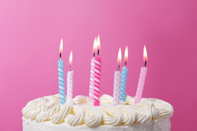 Delicious cake with cream and burning candles on pink background, closeup