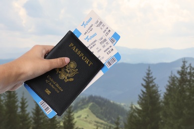 Image of Woman holding passport with tickets in mountains, closeup. Travel agency service