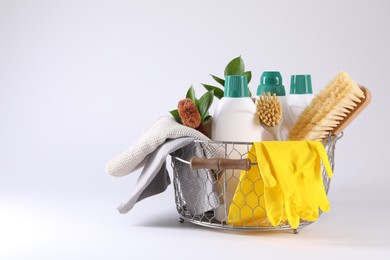 Set of different cleaning supplies in basket on white background