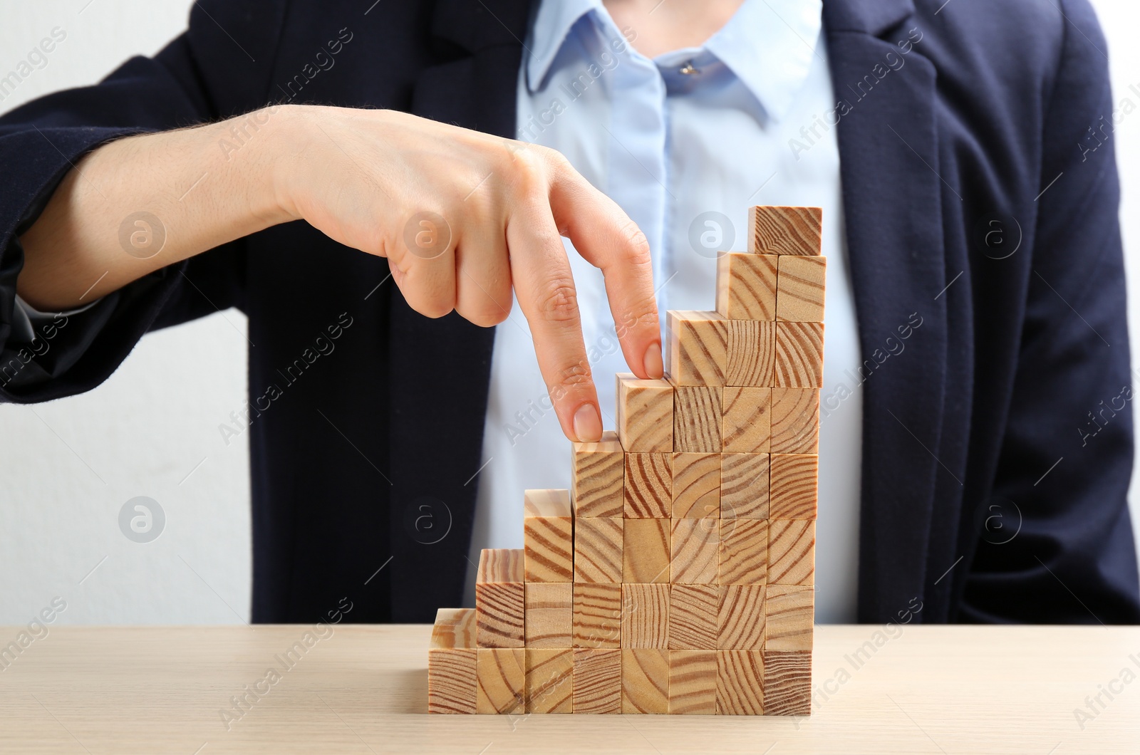 Photo of Woman imitating stepping up on wooden stairs with her fingers at table, closeup. Career promotion  concept