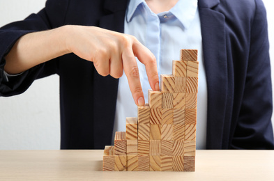 Photo of Woman imitating stepping up on wooden stairs with her fingers at table, closeup. Career promotion  concept