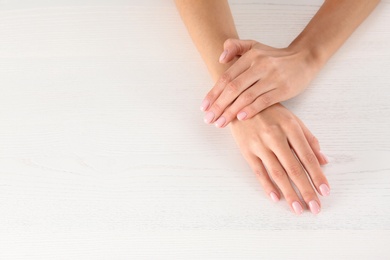 Closeup view of woman with beautiful hands at white wooden table, space for text. Spa treatment