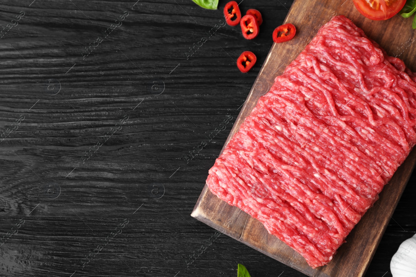 Photo of Flat lay composition with fresh raw minced meat on black wooden table. Space for text