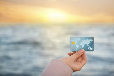 Photo of Woman holding credit card against sea, closeup view