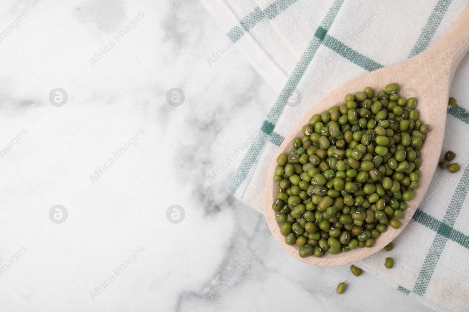 Photo of Wooden spoon with mung beans on white marble table, flat lay. Space for text