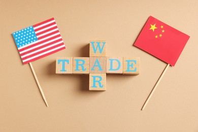 Photo of Wooden cubes with words Trade War, American and Chinese flags on beige background, flat lay