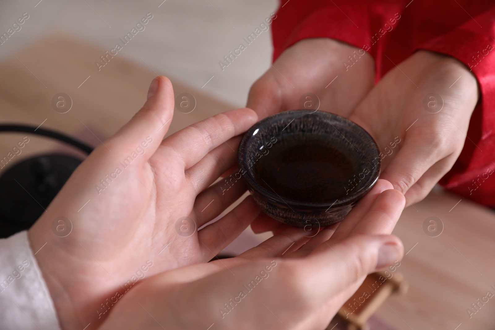 Photo of Master giving freshly brewed tea to guest during ceremony at table, closeup