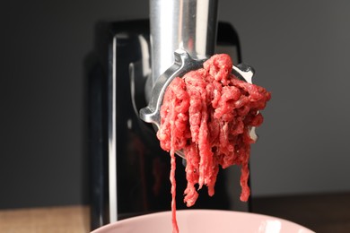 Photo of Electric meat grinder with beef mince against grey background, closeup