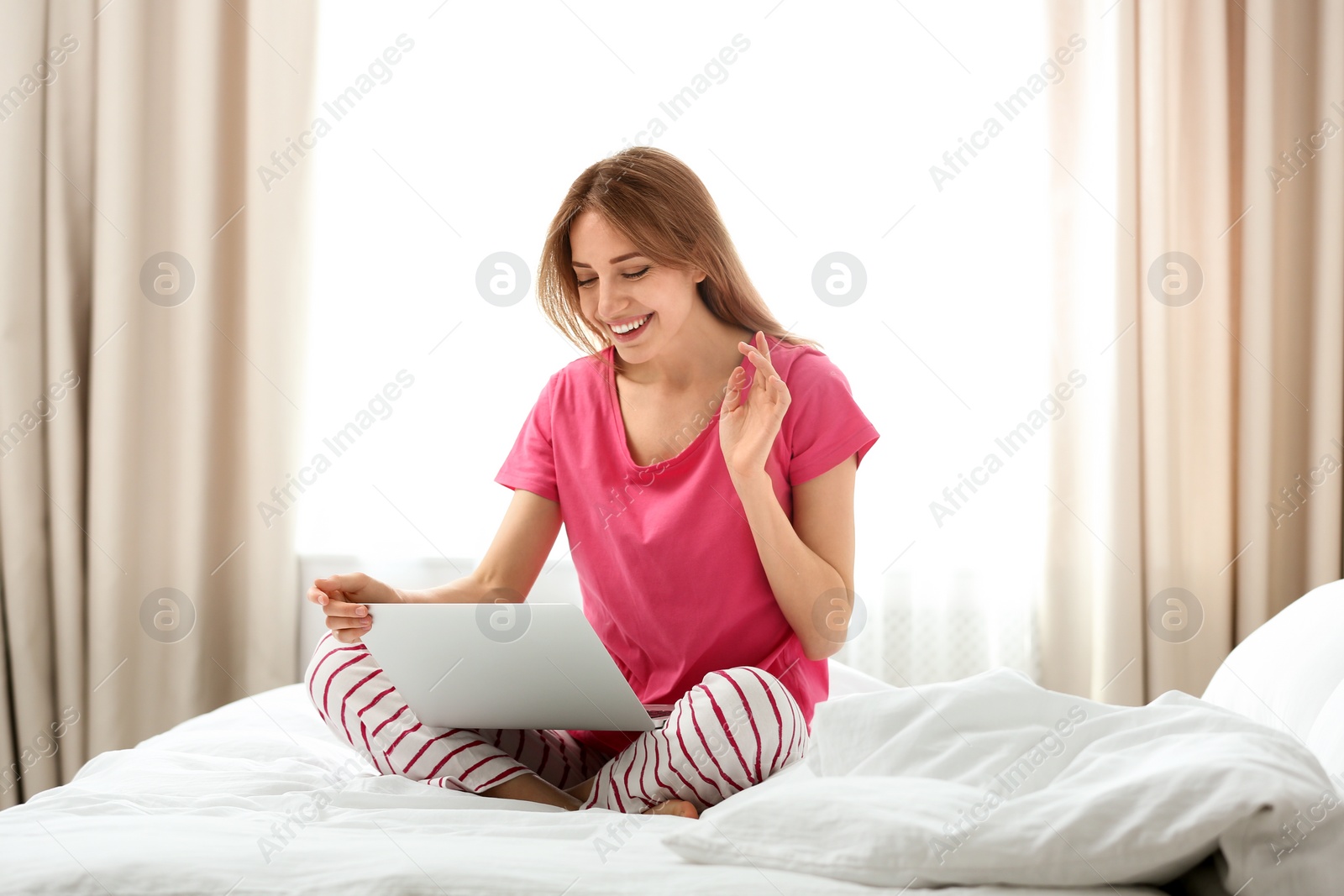 Photo of Young woman using modern laptop in bedroom