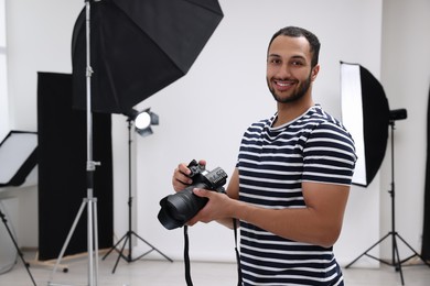 Photo of Professional photographer with camera in modern photo studio, space for text