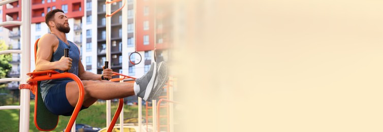 Handsome man doing abs exercise at outdoor gym, space for text. Banner design