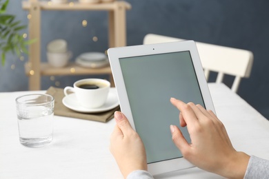 Young woman using new modern tablet in kitchen, closeup