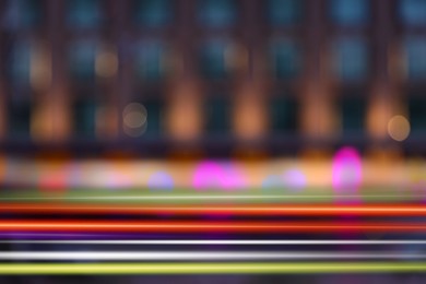 Blurred view of building and light trails in city, motion blur effect