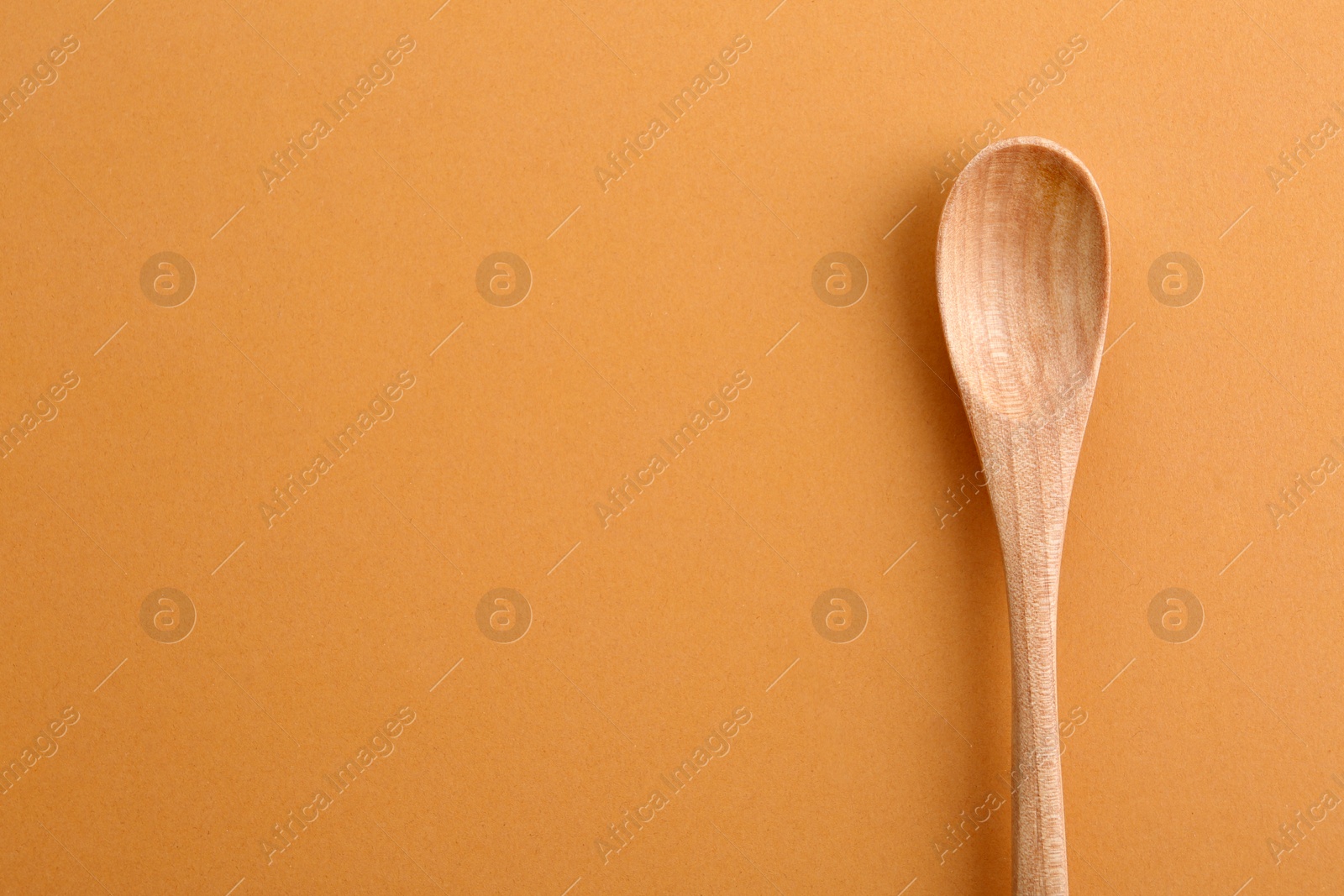 Photo of Clean wooden spoon and space for text on color background, top view