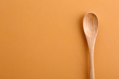 Photo of Clean wooden spoon and space for text on color background, top view