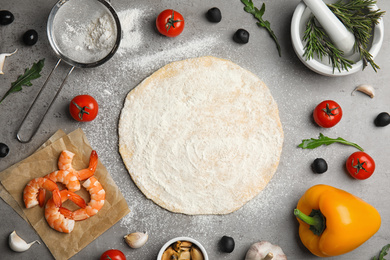 Flat lay composition with dough and fresh ingredients for seafood pizza on grey table