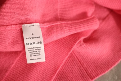 Photo of Clothing label on coral garment, closeup view