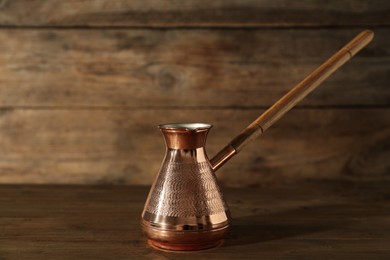 Photo of Beautiful copper turkish coffee pot on wooden table