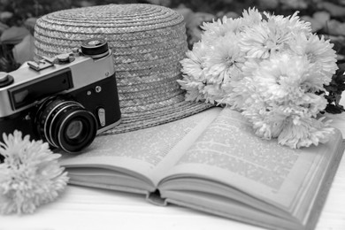 Image of Composition with beautiful chrysanthemum flowers, vintage camera and book on table outdoors, closeup. Black and white effect