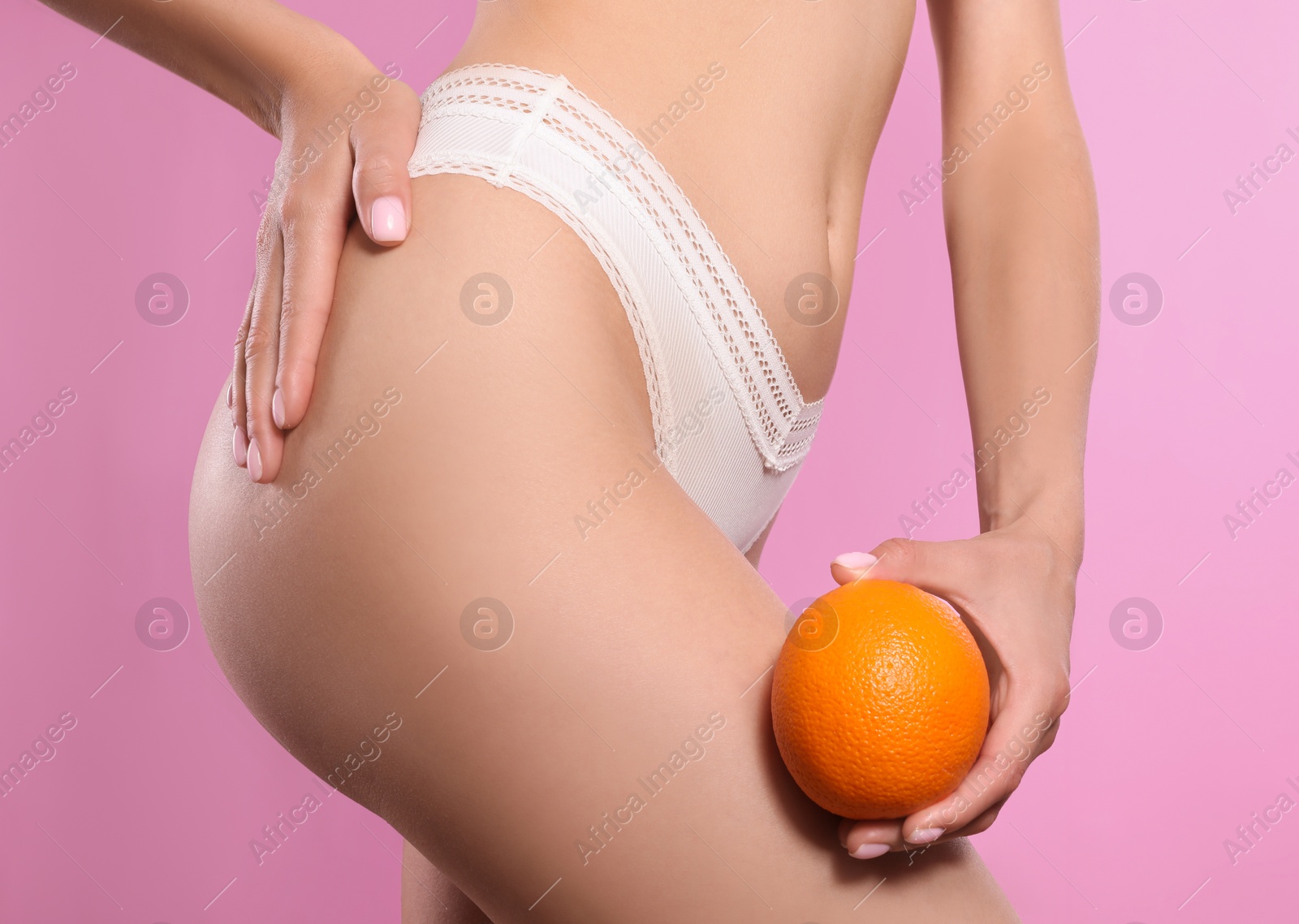 Photo of Closeup view of slim woman in underwear with orange on pink background. Cellulite problem concept