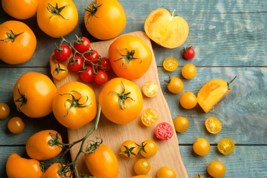 Photo of Ripe yellow and red tomatoes on light blue wooden table, flat lay