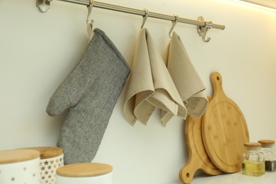 Photo of Kitchen towels and glove for hot dishes hanging on hook rack indoors