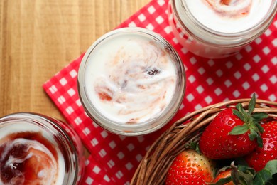 Photo of Tasty yoghurt with jam and strawberries on wooden table, top view