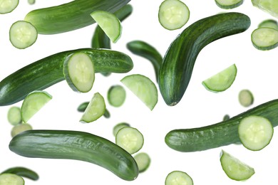 Fresh green cucumbers falling on white background