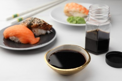 Photo of Tasty soy sauce and sushi on white marble table