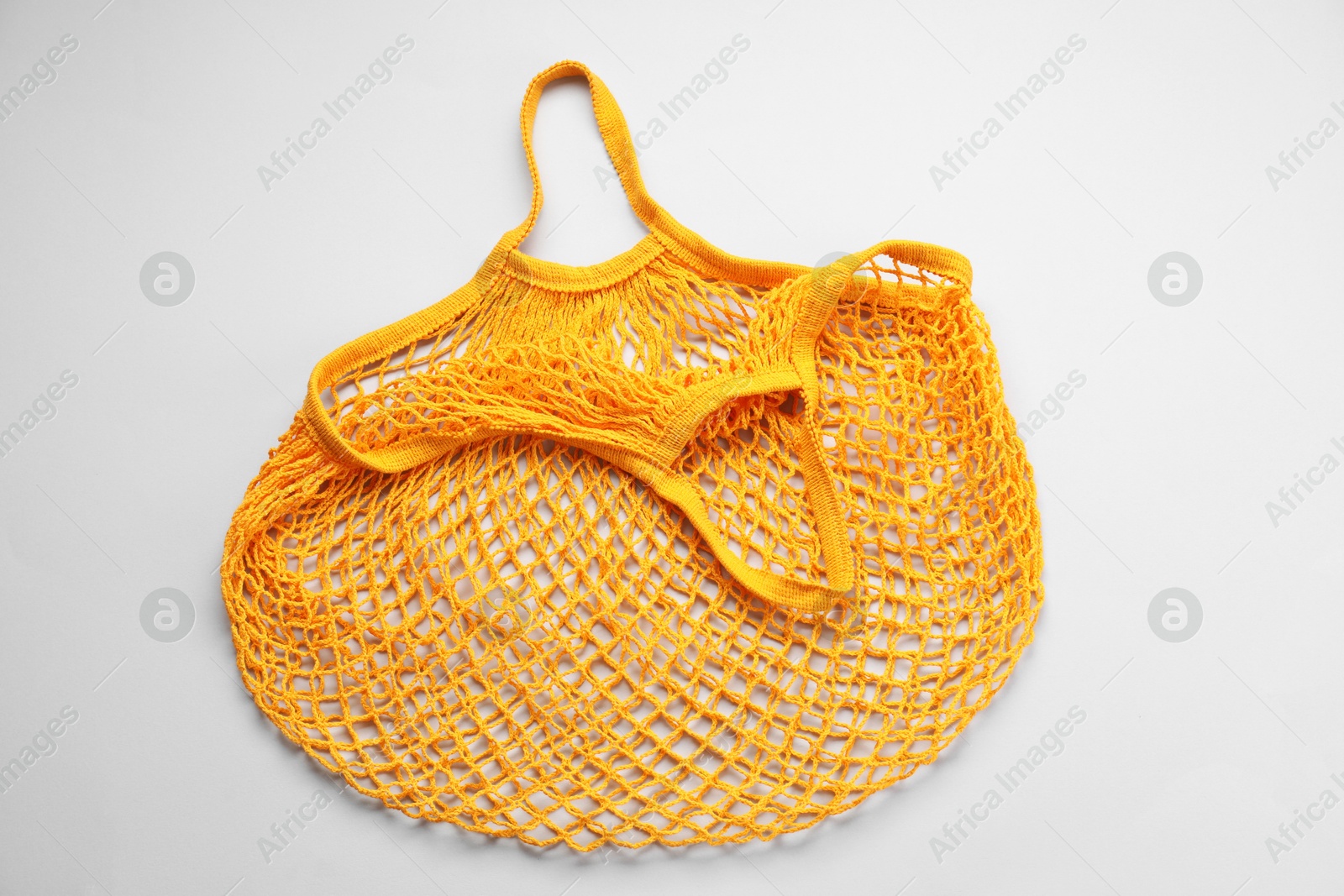 Photo of Orange string bag on light grey background, top view