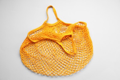 Orange string bag on light grey background, top view