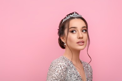 Beautiful young woman wearing luxurious tiara on pink background, space for text