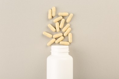 Photo of Bottle and vitamin capsules on light background, top view