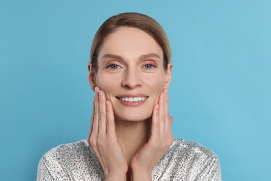 Woman massaging her face on turquoise background