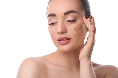 Woman with swatches of foundation on face against white background