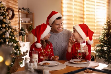 Photo of Happy father and his children eating delicious Christmas cookies at home
