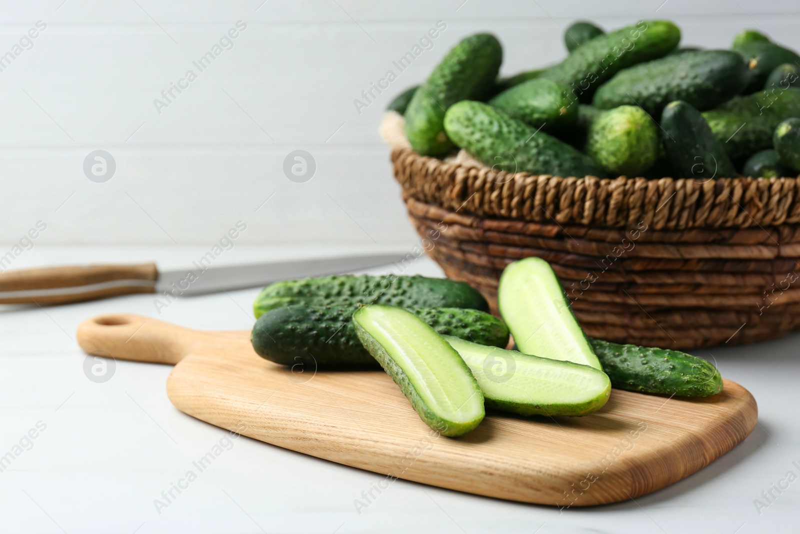 Photo of Whole and cut fresh ripe cucumbers on white table