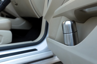 Photo of Silver thermos in door storage pocket inside car
