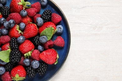 Different fresh ripe berries on light wooden table, top view. Space for text