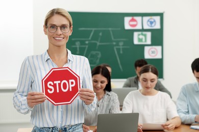 Photo of Teacher showing Stop road sign during lesson in driving school