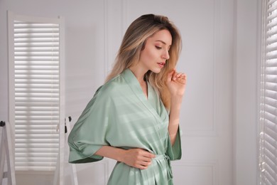 Photo of Pretty young woman in beautiful silk robe at home