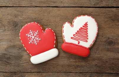 Photo of Mitten shaped Christmas cookies on wooden table, flat lay
