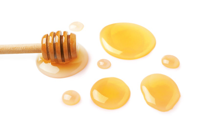 Photo of Drops of honey and dipper on white background