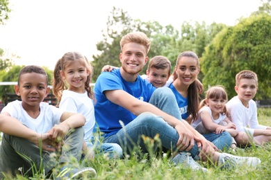 Photo of Volunteers and kids sitting on grass in park