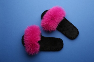 Photo of Pair of soft slippers on blue background, flat lay
