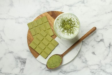 Photo of Pieces of tasty matcha chocolate bar, drink and powder on white marble table, top view