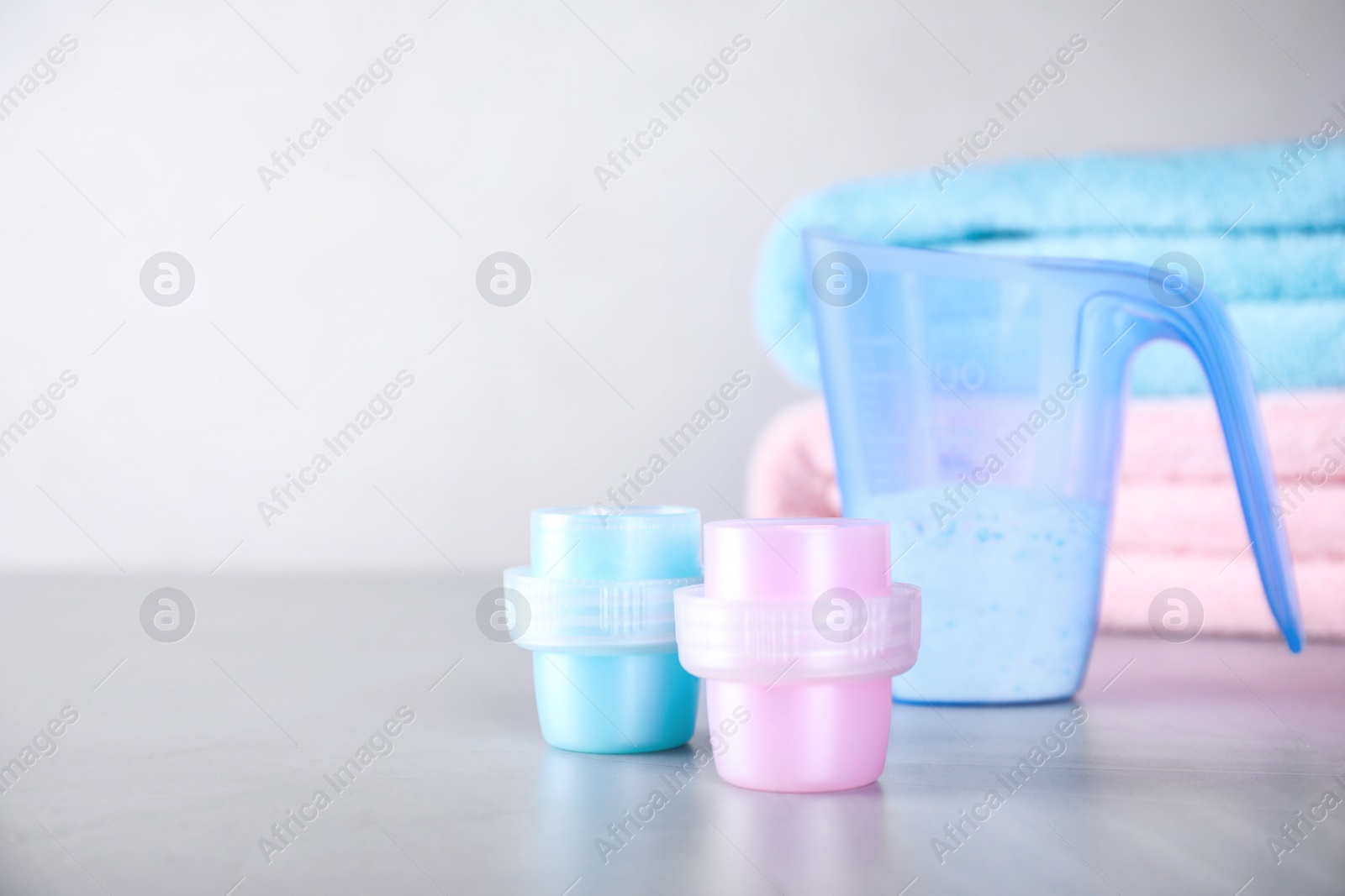 Photo of Laundry detergents on grey table against blurred background. Space for text