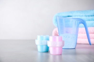 Photo of Laundry detergents on grey table against blurred background. Space for text